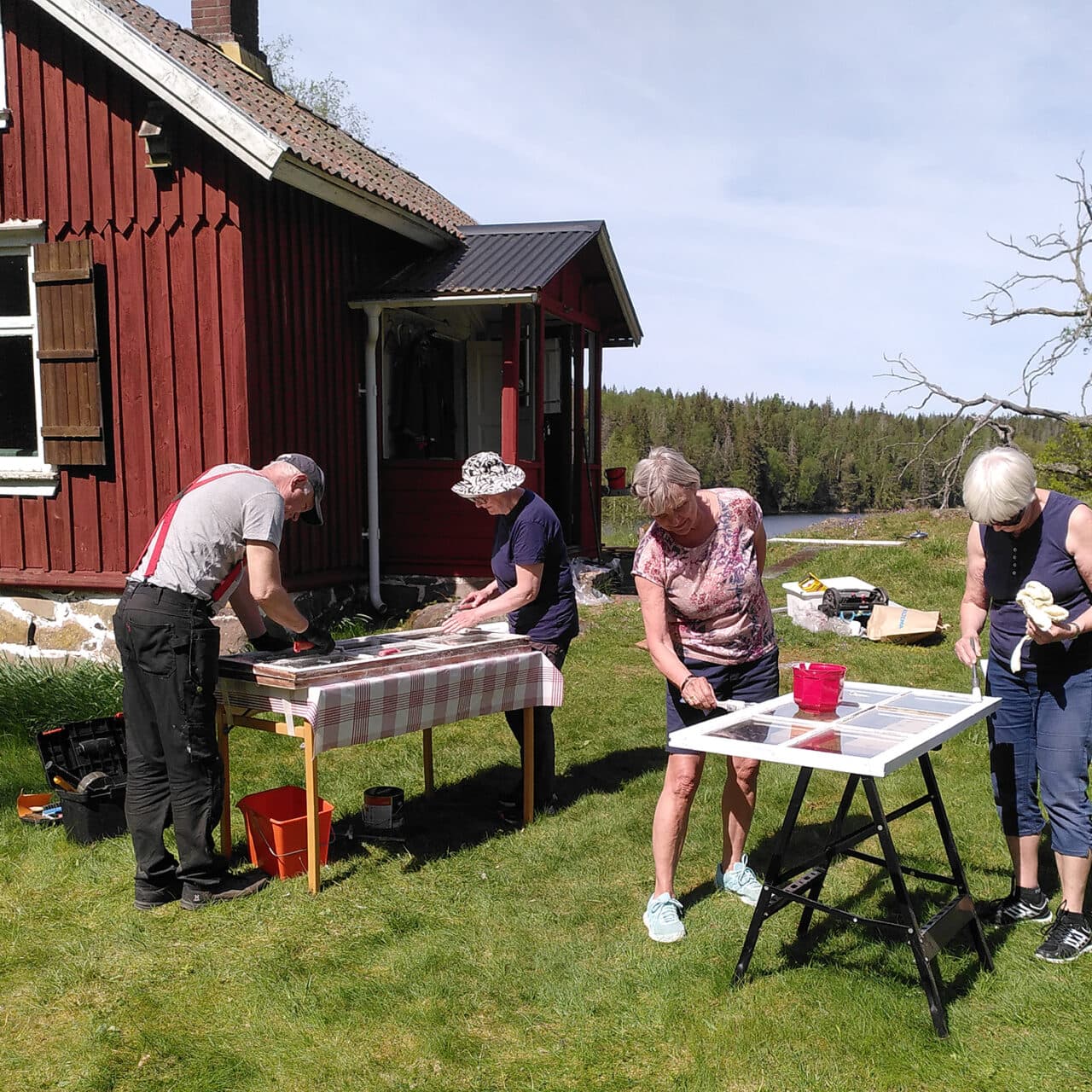 Fyra personer håller på att renovera och måla fönster till Grinnsjötorp