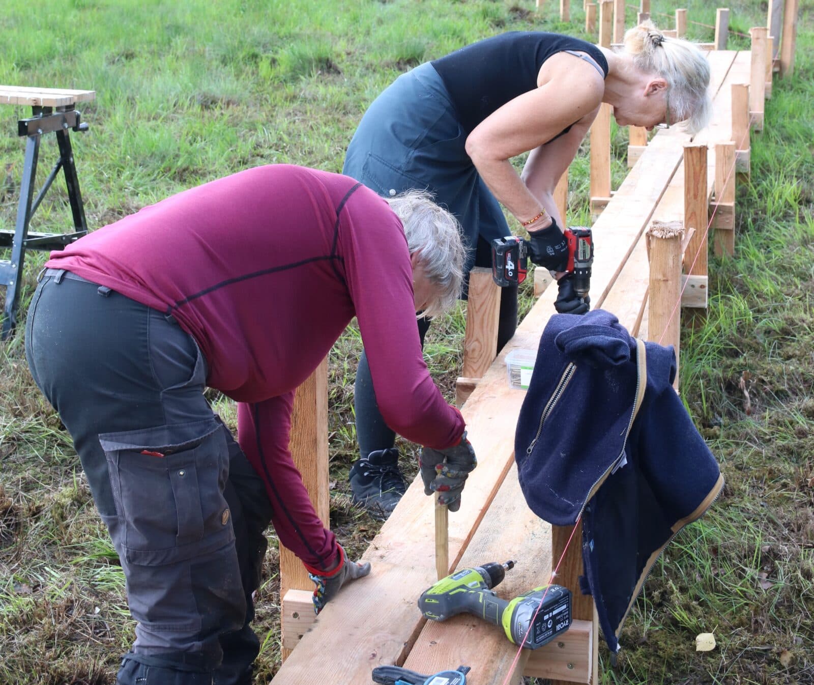 Två volontärer jobbar med att skruva fast en ny spång vid Grinnsjötorp